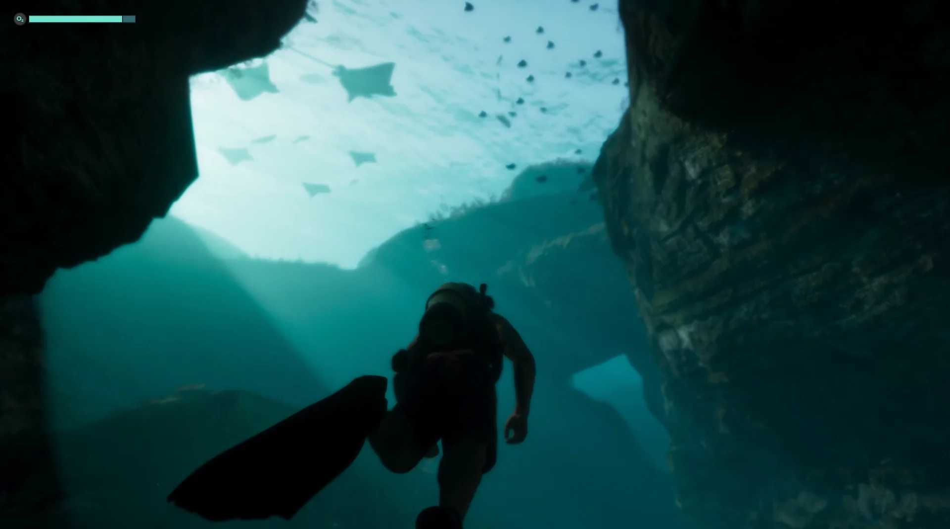 A scuba diver swims through a rocky underwater passage as rays and schools of fish pass overhead in Grand Theft Auto VI.