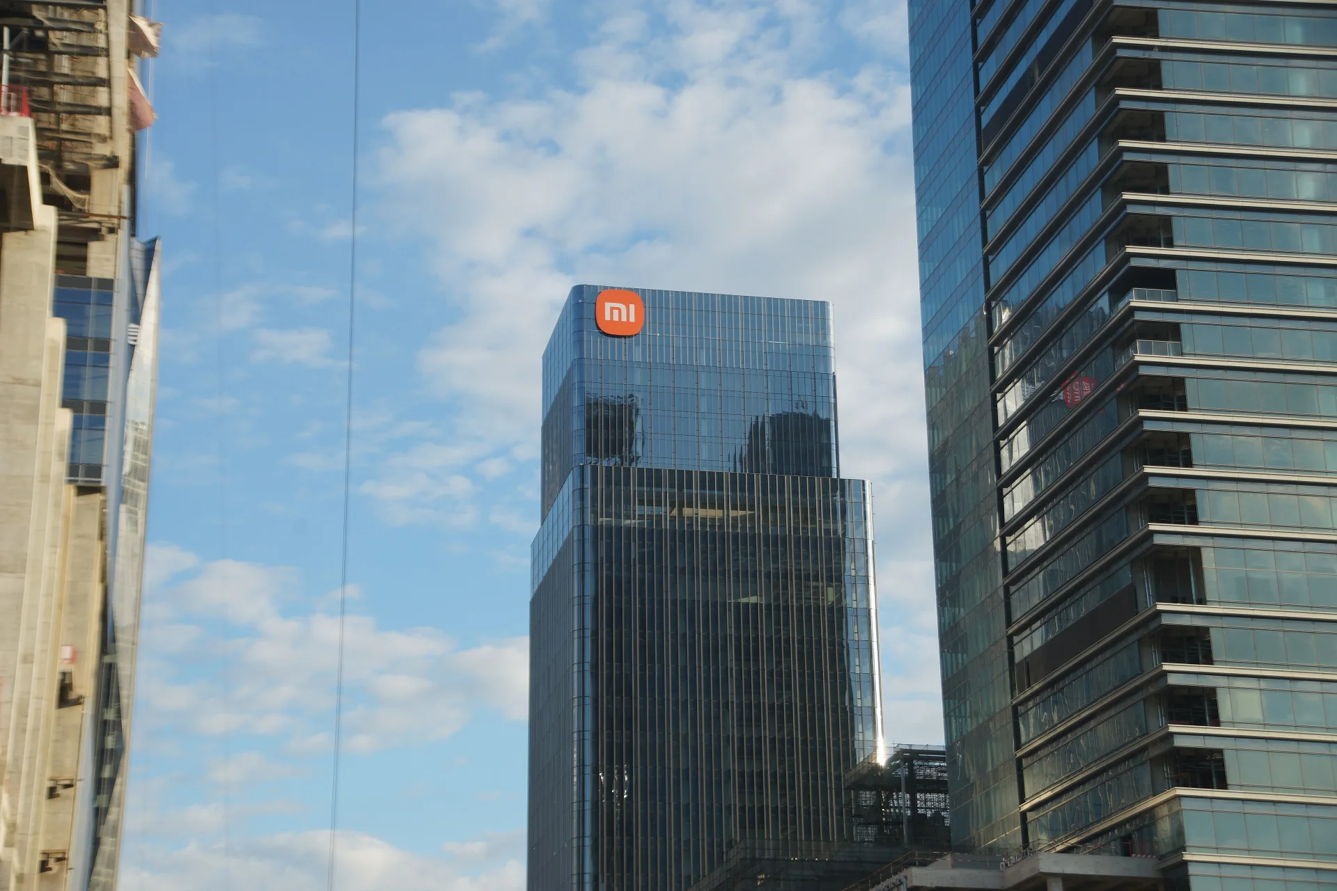 The glass-fronted Xiaomi Building in Guangzhou, with the orange Xiaomi logo near the top.